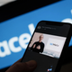 A smartphone showing Facebook founder Mark Zuckerberg talking about the "metaverse" overlaid over the Facebook logo.